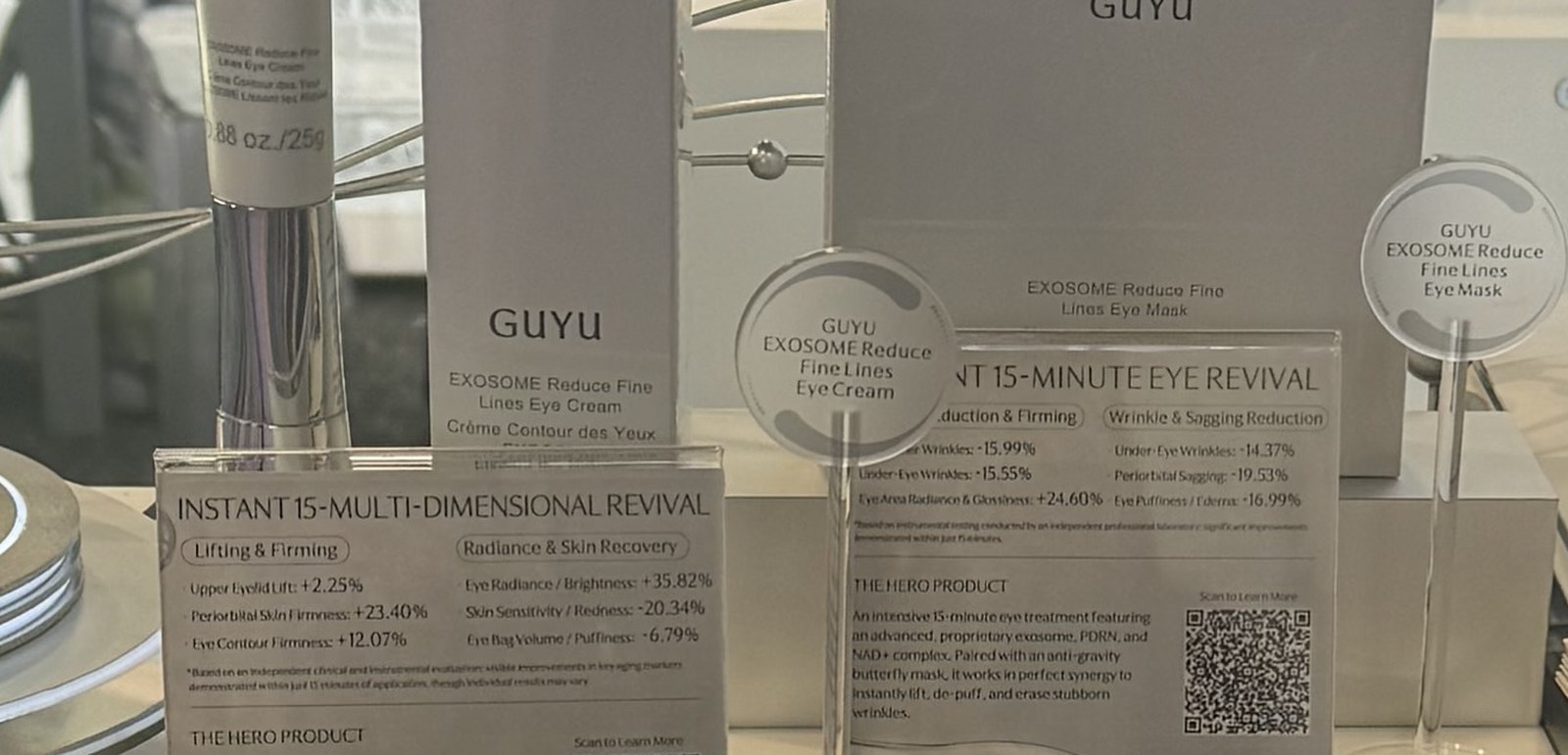 Acrylic claim cards on a trade show table listing percentage improvements in eyelid lift, firmness, radiance and puffiness