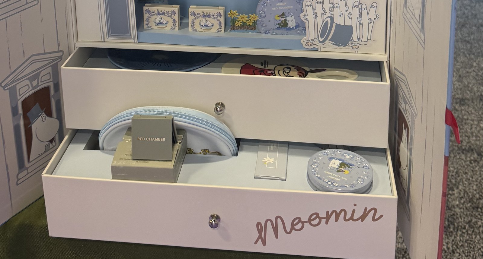 Open drawers of a licensed beauty gift set containing a zip pouch, a compact, a slim palette and an illustrated tin
