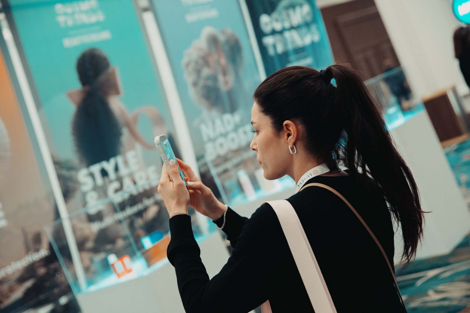 A visitor photographing a product display case at the CosmoTrends showcase