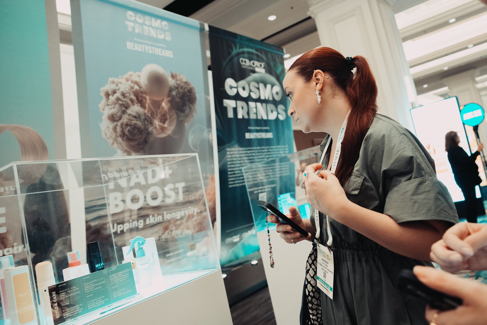 A visitor photographing the NAD+ Boost display case at the CosmoTrends showcase